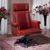 Red leather executive chair with a high back and a headrest, mounted on a swivel base with black casters.