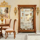 Luxurious handcrafted Italian furniture with ornate woodwork, featuring a classic display cabinet in an elegant interior.