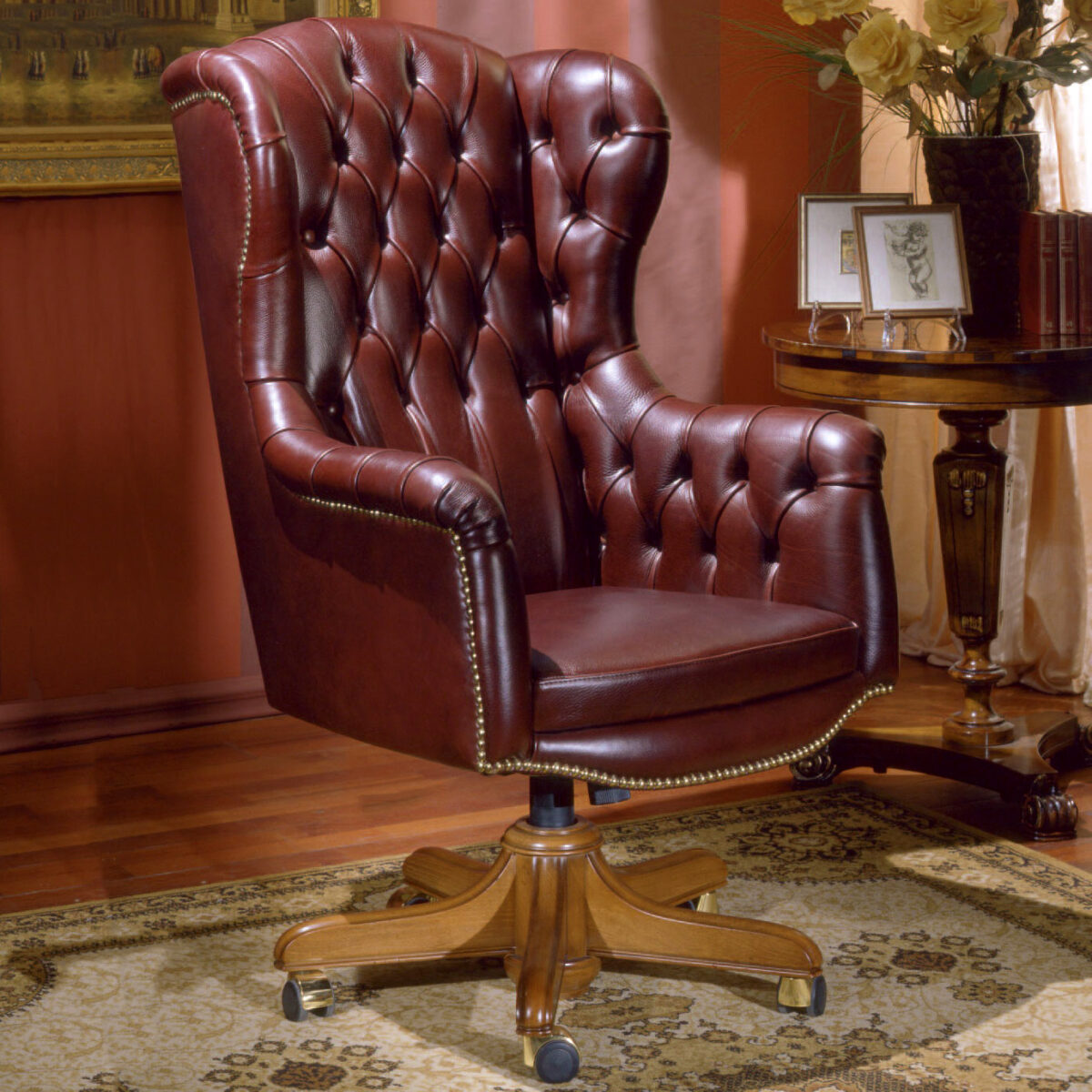 Poltrona direzionale in pelle bordeaux con schienale trapuntato, borchie in ottone e base in legno con ruote
