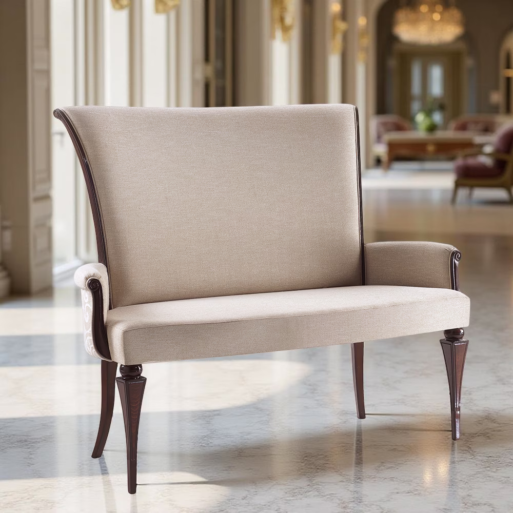 Divanetto imbottito beige con gambe e braccioli in legno scuro, ambientato in uno spazio elegante con pavimento in marmo, grandi finestre e lampadari