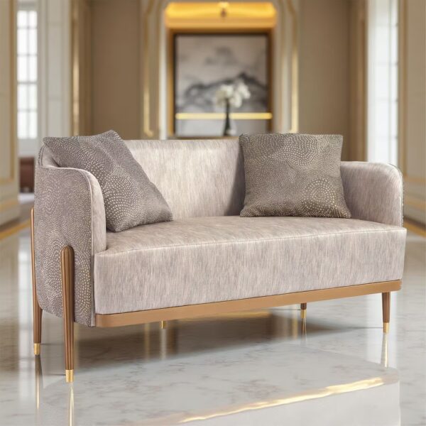 A modern sofa in beige fabric with decorative cushions and golden details, set in an elegant living room with marble flooring.