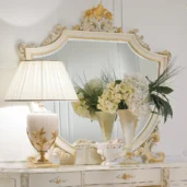 Elegant Italian handcrafted wood dresser with ornate mirror, decorative lamp, and floral arrangement.