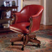 Red leather presidential armchair with a curved back and rolled arms, mounted on a swivel base with brass casters.