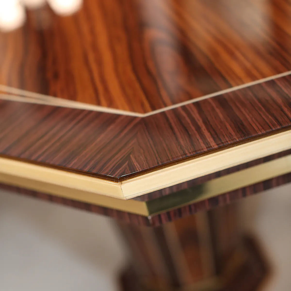 Close-up of elegant handmade wooden table corner with luxurious grain and gold accents, crafted by Italian artisans.
