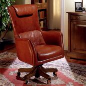 Brown leather executive chair with a high back and a headrest, mounted on a swivel base with brass casters.