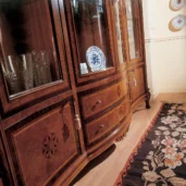 Elegant handmade wooden cabinet with glass doors displaying crystal and china, crafted by Italian artisans.