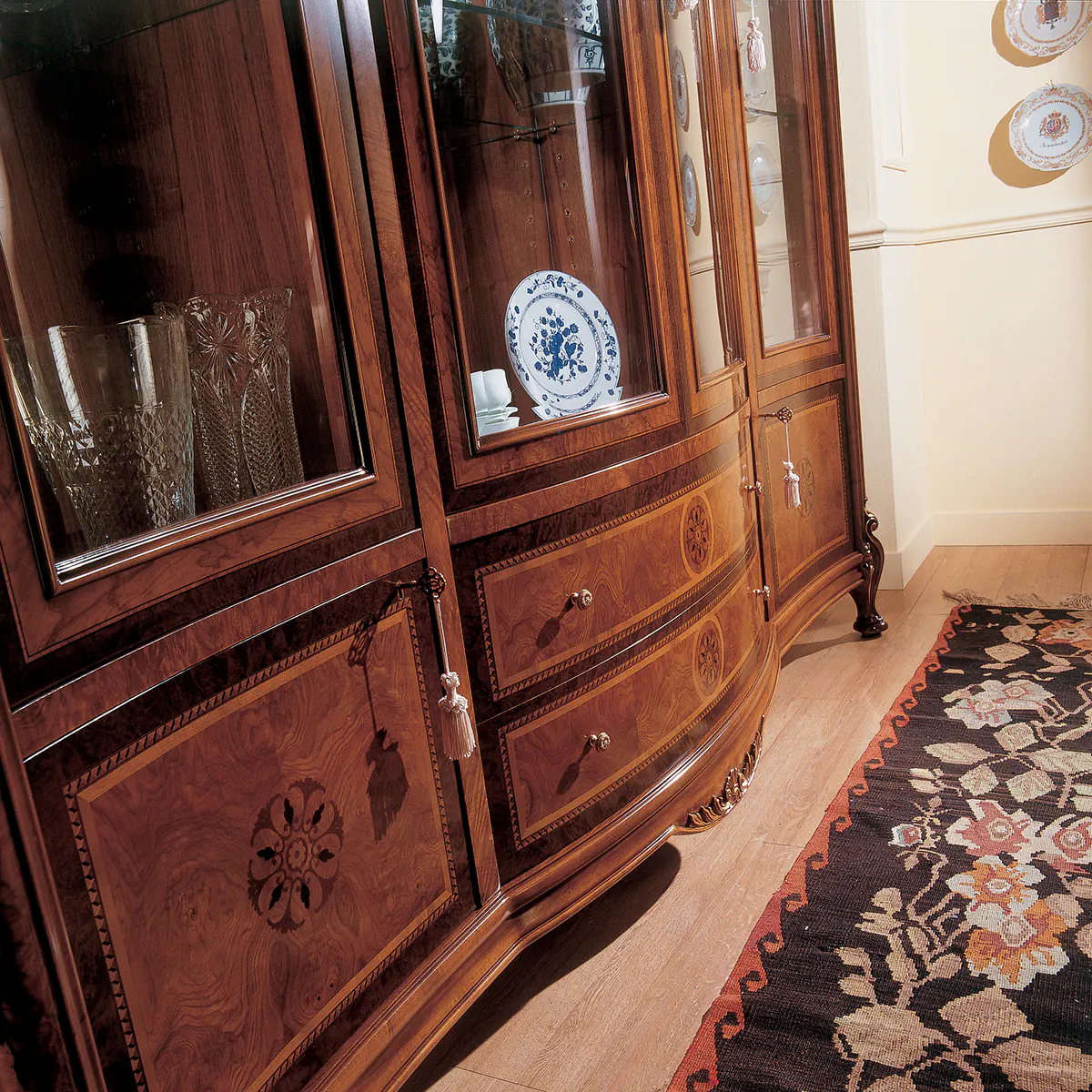 Elegant handmade wooden cabinet with glass doors displaying crystal and china, crafted by Italian artisans.