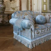 Luxurious Italian sofa with intricate patterns and tassels in an elegant room setting. High-end design furniture.