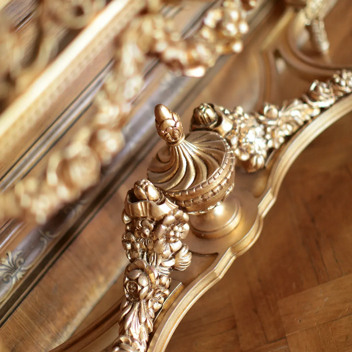 Ornate gold wood carving detail on handcrafted Italian furniture for luxury villas and palaces, emphasizing elegance.