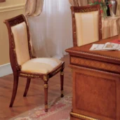 Elegant handcrafted wooden chair and desk in a luxurious Italian villa interior, featuring elaborate details and rich finishes.