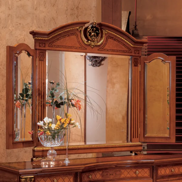 Elegant handcrafted wooden mirror with intricate details, reflecting floral arrangement, in luxury villa interior setting.