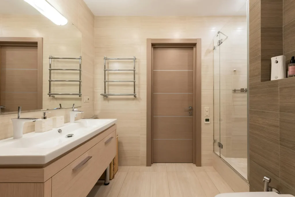 Un moderno mobile bagno su misura realizzato in legno chiaro con lavabo sospeso, specchio a parete e mobiletto sottolavabo con cassetti e ante. Il mobile bagno è completato da faretti a LED e da una finitura elegante e raffinata.