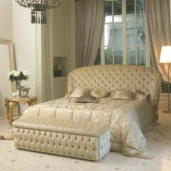 Bed with embroidered velvet headboard and frame, elegant wood carvings, and gold leaf finish