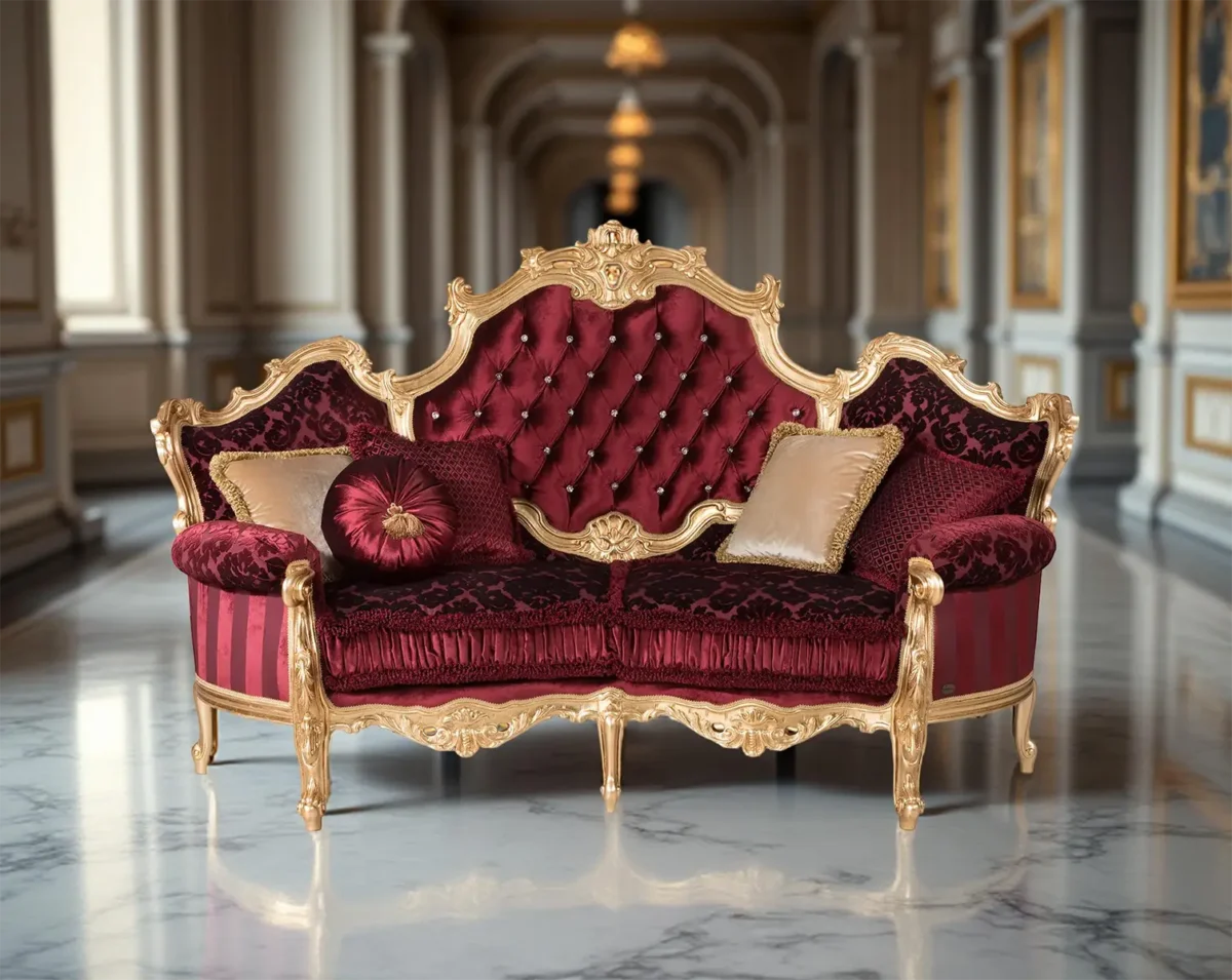 Ein luxuriöses Sofa mit goldenem Gestell und rotem, gestepptem Bezug, verziert mit goldenen und roten Kissen, platziert in einem eleganten Raum mit Marmorboden, Säulen und Wandleuchten.