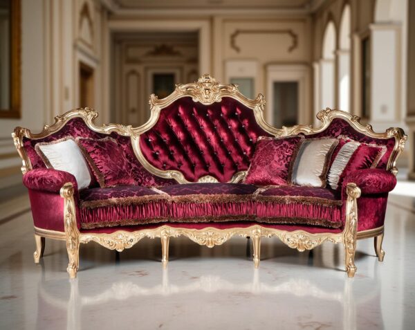 Divano lussuoso con rivestimento in velluto rosso e dettagli dorati, schienale alto trapuntato e cuscini decorativi, ambientato in una stanza elegante con colonne e stucchi classici
