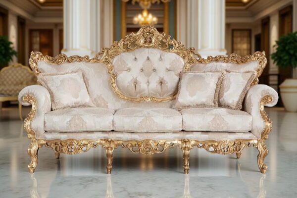 A luxurious sofa with golden details and floral beige upholstery, a tufted backrest and decorative cushions, set in an elegant space with marble flooring and columns.