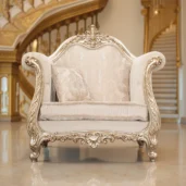 Poltrona Wagner in stile barocco con struttura in legno intagliato dorato, rivestita in tessuto chiaro damascato con lavorazione capitonné.