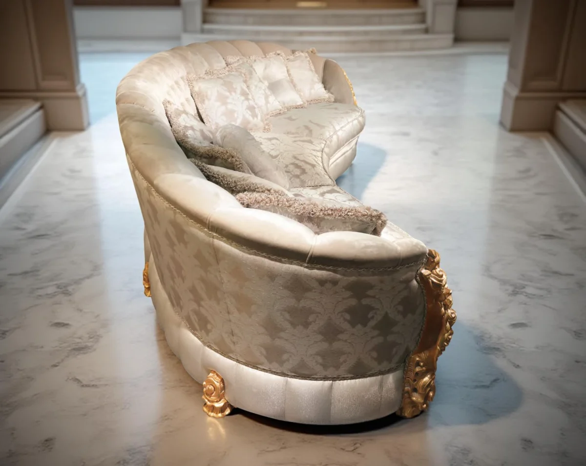 Divano curvo di lusso con dettagli dorati, tessuto chiaro decorato e cuscini eleganti in un atrio con colonne e pavimento in marmo.