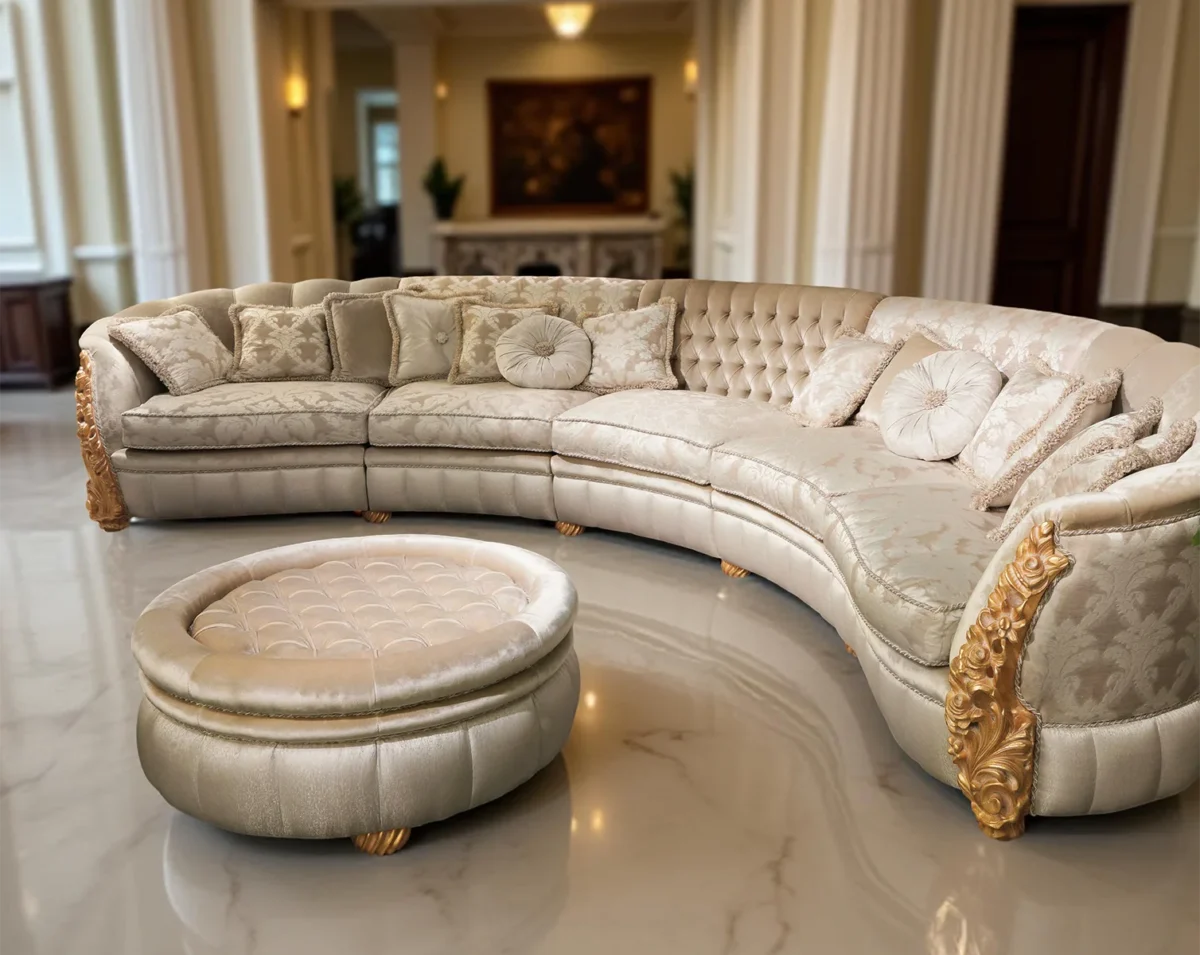 Divano curvo di lusso con dettagli dorati, tessuto chiaro decorato e cuscini eleganti in un atrio con colonne e pavimento in marmo.