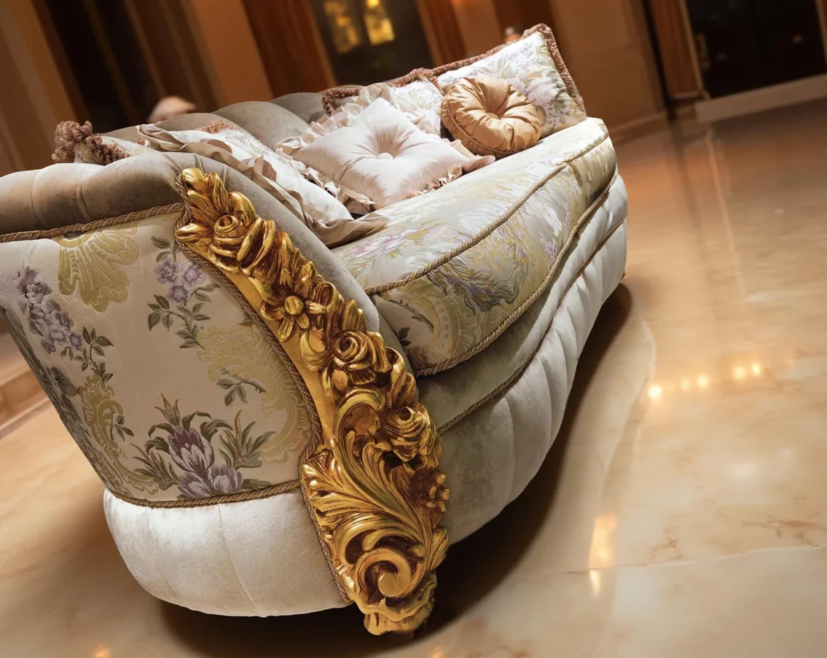 Divano curvo di lusso con dettagli dorati, tessuto chiaro decorato e cuscini eleganti in un atrio con colonne e pavimento in marmo.