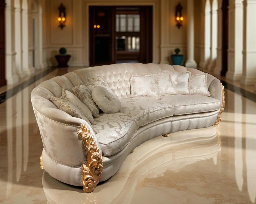 Luxuriöses, geschwungenes Sofa mit goldenen Akzenten, hellem Stoff und eleganten Kissen in einer Halle mit Marmorboden und Säulen.