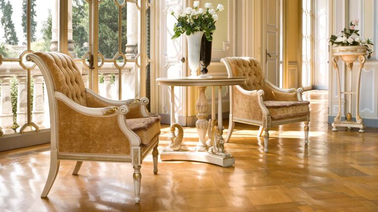 Due poltrone classiche in velluto color oro con dettagli intagliati e dorati, tavolino centrale intarsiato, arredamento elegante in stile neoclassico