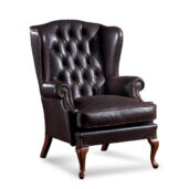 Poltrona wingback in pelle nera, schienale capitonné, braccioli arrotolati, bordatura con borchie e gambe in legno a cabriole.