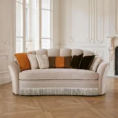 Champagne velvet curved sofa with scalloped shell back, rope piping and bullion fringe, Art Deco-inspired.
