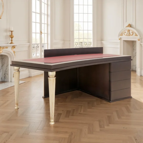 Chefschreibtisch aus dunklem Holz mit bordeauxroter Lederauflage, goldenen kannelierten Beinen und seitlichem Schubladencontainer, modern-klassisch.