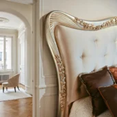 King-size pearl velvet bed with scalloped tufted headboard and carved frame in silver and gold leaf, bronze accent pillows.