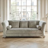 Divano classico con rivestimento floreale color crema e piedini intagliati a forma di conchiglia in un elegante ambiente luminoso