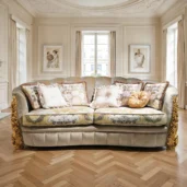 Divano classico con velluto chiaro, cuscini floreali decorativi e intagli dorati in un salotto raffinato