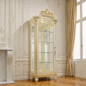 Роскошная витрина цвета слоновой кости с золотым декором: стеклянный фронт, стеклянные полки и резной карниз на точёных опорах в классическом интерьере.