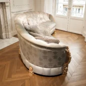 Divano modulare curvo in tessuto damascato con cuscini coordinati e dettagli dorati in un salotto elegante