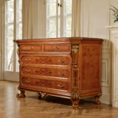 Luxuriöse Kommode aus honigfarbenem Maserholz mit Intarsien, vergoldeten Profilen, geschnitzten Pilastern, Messinggriffen und geschwungenen Füßen in elegantem klassischem Interieur.