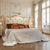 King-size pearl velvet bed with scalloped tufted headboard and carved frame in silver and gold leaf, bronze accent pillows.