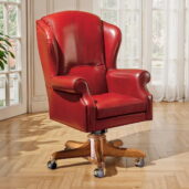 Кресло руководителя Marzorati из красной кожи с высокой спинкой в стиле wingback, закруглёнными подлокотниками, съёмной подушкой сиденья и деревянным поворотным основанием на колёсиках.