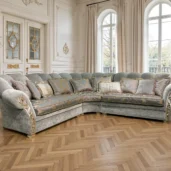 Divano angolare classico in velluto verde con ricami damascati e finiture dorate in un salone elegante