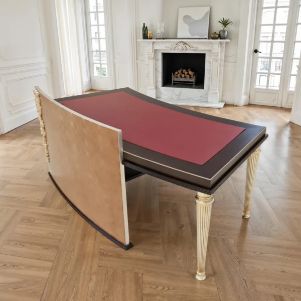 Chefschreibtisch aus dunklem Holz mit bordeauxroter Lederauflage, goldenen kannelierten Beinen und seitlichem Schubladencontainer, modern-klassisch.