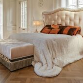 King-size pearl velvet bed with scalloped tufted headboard and carved frame in silver and gold leaf, bronze accent pillows.