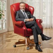 Luxurious vibrant red leather executive swivel armchair with classic wingback design, placed in a bright lounge with windows and plant, perfect for high-end home office furniture and energetic, elegant comfort.