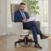 Sleek beige leather executive armchair with segmented high back, dark wood swivel base and wheels, perfect for modern luxury offices.