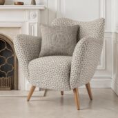 Poltrona moderna compatta con rivestimento in tessuto geometrico grigio, gambe in legno e cuscino coordinato