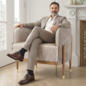 Poltrona artigianale italiana in tessuto con gambe in legno e terminali dorati, ideale per salotti di lusso e ambienti contemporanei.