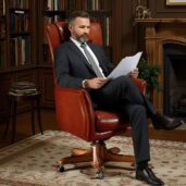 Elegant high-back executive armchair in premium brown leather with wooden swivel base, crafted by Marzorati for luxury offices.
