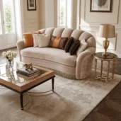 Luxury living room sofa with curved back, fringe detail and decorative cushions, upholstered in soft neutral Italian fabrics.