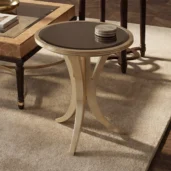 Studio shot of a gold occasional table featuring a dark bronzed mirror top and sleek curved tripod legs