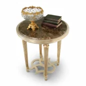 Studio shot of a luxury round side table with brown marble top and fluted gold legs, featuring a crystal bowl and antique books prop