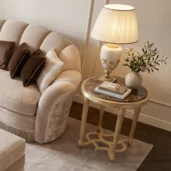 Round end table featuring dark Emperador marble top and gold leaf fluted legs positioned next to a velvet sofa in a luxury living room