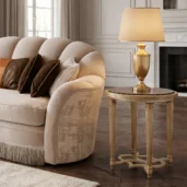 Round end table featuring dark Emperador marble top and gold leaf fluted legs positioned next to a velvet sofa in a luxury living room